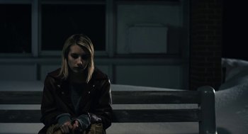Movie still from “The Blackcoat's Daughter” (2015), directed by Oz Perkins – A woman in a brown jacket standing next to a wooden railing; Medium shot, High angle