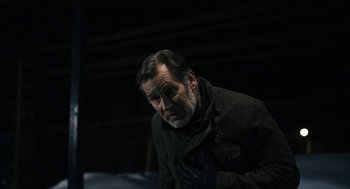 Movie still from “The Blackcoat's Daughter” (2015), directed by Oz Perkins – An older man wearing a black jacket looking at the camera; Medium shot, Over the shoulder angle