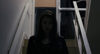 Movie still from “The Blackcoat's Daughter” (2015), directed by Oz Perkins – A woman wearing a leather jacket standing on stairs; Close Up shot, Low angle
