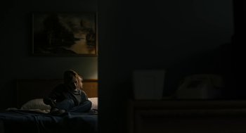 Movie still from “The Blackcoat's Daughter” (2015), directed by Oz Perkins – A woman sitting on a bed in a dark room; Wide shot, High angle