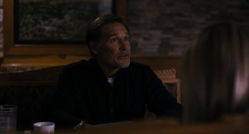 Movie still from “The Blackcoat's Daughter” (2015), directed by Oz Perkins – A man sitting at a table in front of a brick wall; Medium shot, Over the shoulder angle