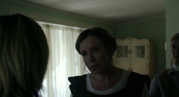 Movie still from “The Blackcoat's Daughter” (2015), directed by Oz Perkins – A woman looking into a mirror in a dark room; Close Up shot, Over the shoulder angle