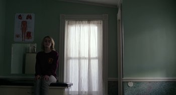 Movie still from “The Blackcoat's Daughter” (2015), directed by Oz Perkins – A woman sitting in front of a window in a room; Medium shot, Low angle
