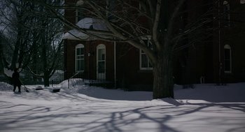 Movie still from “The Blackcoat's Daughter” (2015), directed by Oz Perkins – A tree is in the middle of a snowy yard; Extreme Wide shot, High angle