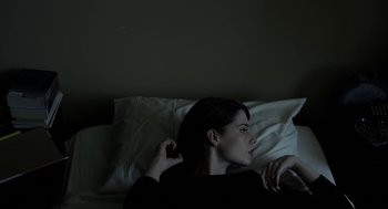 Movie still from “The Blackcoat's Daughter” (2015), directed by Oz Perkins – A woman laying in a bed while talking on the phone; Close Up shot, High angle