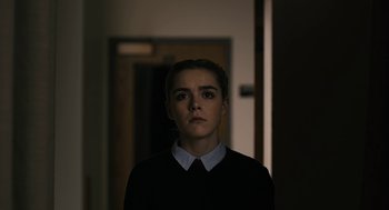 Movie still from “The Blackcoat's Daughter” (2015), directed by Oz Perkins – A woman in a black shirt and white shirt looking at the camera; Medium shot, Over the shoulder angle