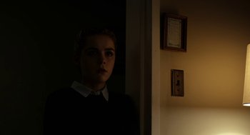 Movie still from “The Blackcoat's Daughter” (2015), directed by Oz Perkins – A woman standing in a dark room looking at the camera; Close Up shot, Low angle