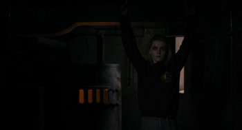 Movie still from “The Blackcoat's Daughter” (2015), directed by Oz Perkins – A woman standing in the dark holding her arms up; Medium shot, Low angle