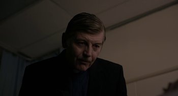 Movie still from “The Blackcoat's Daughter” (2015), directed by Oz Perkins – A person wearing a suit and tie; Close Up shot, Over the shoulder angle