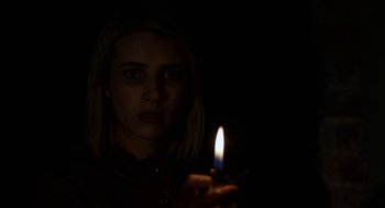 Movie still from “The Blackcoat's Daughter” (2015), directed by Oz Perkins – A woman is holding a candle in the dark; Close Up shot, Low angle