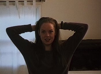 Movie still from “The Blair Witch Project” (1999), directed by Eduardo Sánchez – A woman with her hands behind her head in front of a window; Close Up shot, High angle