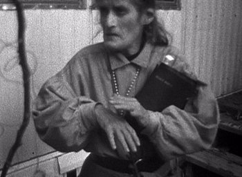 Movie still from “The Blair Witch Project” (1999), directed by Eduardo Sánchez – An older woman holding a book in her hands; Medium shot, High angle