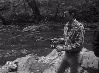 Movie still from “The Blair Witch Project” (1999), directed by Eduardo Sánchez – A black and white photo of a man holding a fishing rod; Medium shot, High angle