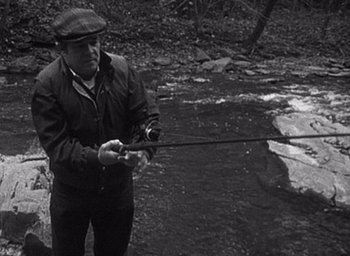 Movie still from “The Blair Witch Project” (1999), directed by Eduardo Sánchez – A black and white photo of a man holding a fishing rod; Medium shot, High angle