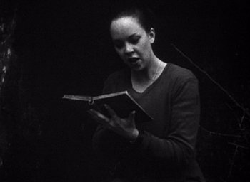 Movie still from “The Blair Witch Project” (1999), directed by Eduardo Sánchez – A woman is reading a book in a dark room; Medium shot, Low angle