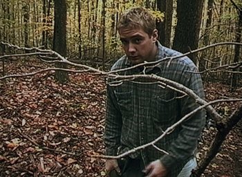 Movie still from “The Blair Witch Project” (1999), directed by Eduardo Sánchez – A man in the woods looking at the camera; Medium shot, High angle