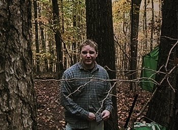 Movie still from “The Blair Witch Project” (1999), directed by Eduardo Sánchez – A man standing next to a tree in the woods; Wide shot, Low angle