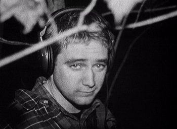 Movie still from “The Blair Witch Project” (1999), directed by Eduardo Sánchez – A black and white photo of a man wearing headphones; Close Up shot, High angle