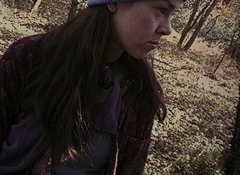 Movie still from “The Blair Witch Project” (1999), directed by Eduardo Sánchez – A woman in a hat walking through the woods; Close Up shot, High angle