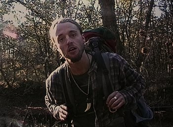 Movie still from “The Blair Witch Project” (1999), directed by Eduardo Sánchez – A man with a backpack walking through the woods; Close Up shot, Low angle