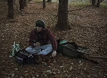 Movie still from “The Blair Witch Project” (1999), directed by Eduardo Sánchez – A man sitting on the ground in the woods; Wide shot, High angle