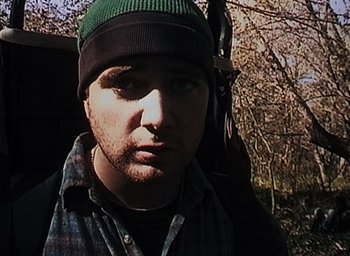 Movie still from “The Blair Witch Project” (1999), directed by Eduardo Sánchez – A person wearing a hat near a tree; Close Up shot, Low angle
