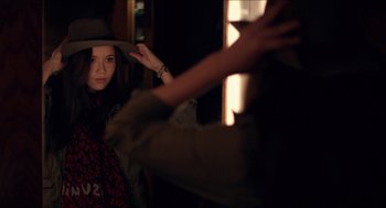 Movie still from “The Bling Ring” (2013), directed by Sofia Coppola – A young woman wearing a cowboy hat in the dark; Medium shot, Over the shoulder angle