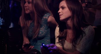 Movie still from “The Bling Ring” (2013), directed by Sofia Coppola – Two young women sitting in front of each other holding cell phones in their hands; Close Up shot, High angle