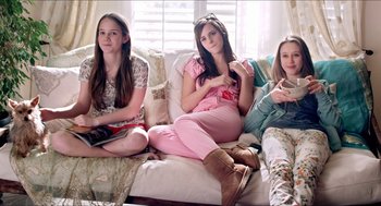Movie still from “The Bling Ring” (2013), directed by Sofia Coppola – Three young women sitting on a couch in front of a window; Medium shot, High angle