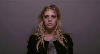 Movie still from “The Bling Ring” (2013), directed by Sofia Coppola – A young woman with long blonde hair and a black jacket; Medium shot, Low angle
