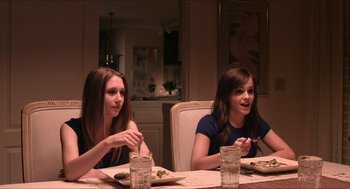Movie still from “The Bling Ring” (2013), directed by Sofia Coppola – Two women sitting at a dinner table with plates of food in front of them; Medium shot, Over the shoulder angle