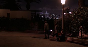 Movie still from “The Bling Ring” (2013), directed by Sofia Coppola – A group of people sitting on the side of a road at night; Extreme Wide shot, High angle