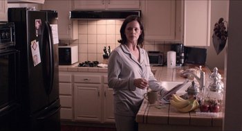 Movie still from “The Bling Ring” (2013), directed by Sofia Coppola – A woman standing in a kitchen holding a coffee cup; Medium shot, Over the shoulder angle