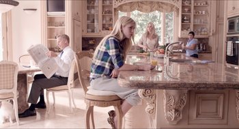 Movie still from “The Bling Ring” (2013), directed by Sofia Coppola – A woman sitting at a kitchen table with a glass of orange juice; Wide shot, Low angle