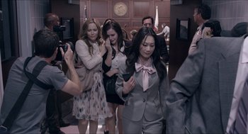 Movie still from “The Bling Ring” (2013), directed by Sofia Coppola – A group of women in a courtroom with a cell phone; Medium shot, Over the shoulder angle