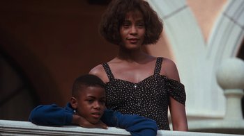 Movie still from “The Bodyguard” (1992), directed by Mick Jackson – A woman standing next to a young boy in front of a building; Close Up shot, Low angle