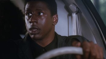 Movie still from “The Bodyguard” (1992), directed by Mick Jackson – A person driving a car on a road; Close Up shot, Low angle