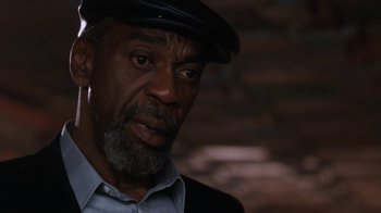 Movie still from “The Bodyguard” (1992), directed by Mick Jackson – An older man wearing a hat and a jacket; Close Up shot, Over the shoulder angle