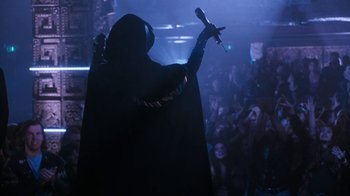 Movie still from “The Bodyguard” (1992), directed by Mick Jackson – A person in a hooded cloak holding a microphone; Wide shot, Low angle