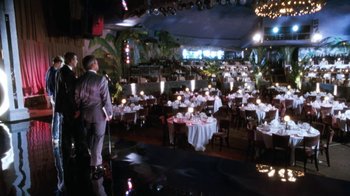 Movie still from “The Bodyguard” (1992), directed by Mick Jackson – A man standing in front of a room filled with tables and chairs; Extreme Wide shot, High angle