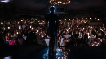 Movie still from “The Bodyguard” (1992), directed by Mick Jackson – A woman standing in front of a crowd of people at an event; Wide shot, Over the shoulder angle