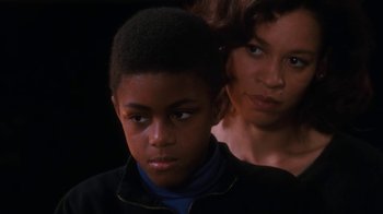 Movie still from “The Bodyguard” (1992), directed by Mick Jackson – A woman standing next to a young boy in front of a dark background; Close Up shot, Low angle
