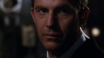 Movie still from “The Bodyguard” (1992), directed by Mick Jackson – A close up picture of a man in a suit; Close Up shot, Over the shoulder angle