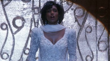 Movie still from “The Bodyguard” (1992), directed by Mick Jackson – A woman in a white dress standing in front of a wall; Medium shot, Low angle