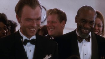 Movie still from “The Bodyguard” (1992), directed by Mick Jackson – A group of men standing next to each other in tuxedos; Close Up shot, Over the shoulder angle