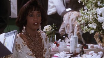 Movie still from “The Bodyguard” (1992), directed by Mick Jackson – A person sitting in front of a table; Close Up shot, Over the shoulder angle