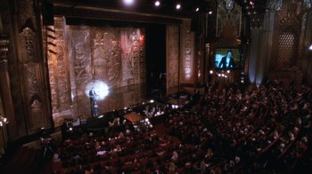 Movie still from “The Bodyguard” (1992), directed by Mick Jackson – An audience is sitting in a theater watching a show; Extreme Wide shot, High angle