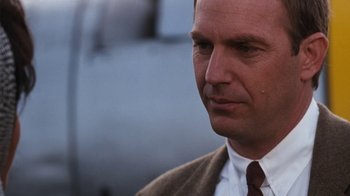 Movie still from “The Bodyguard” (1992), directed by Mick Jackson – A person wearing a suit and tie; Close Up shot, Over the shoulder angle