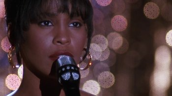 Movie still from “The Bodyguard” (1992), directed by Mick Jackson – A person holding a microphone; Close Up shot, High angle