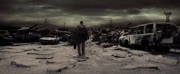 Movie still from “The Book of Eli” (2010), directed by Allen Hughes – A man with a backpack walking through a field of cars; Wide shot, High angle